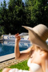 a woman wearing a straw hat sitting next to a pool at Vinte-Quinta da Boavista in Ponte de Lima