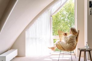 a woman sitting in a chair looking out a window at Boutique Hotel Texel in De Cocksdorp