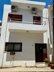 a white building with two windows and a balcony at Arsinoe Guest House in Famagusta