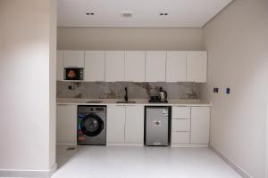 a kitchen with white cabinets and a washing machine at الضيافة المثالية للشقق المخدومة Aldiyafa Serviced Apartments in Jeddah
