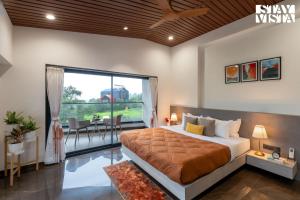 a bedroom with a large bed and a large window at StayVista at Bael Leaf with Projector Setup, Pool in Nashik +39 photos