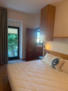 a bedroom with a large white bed and a door at ApartHotel Del Corso in Castiglione della Pescaia