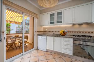 a kitchen with white cabinets and a table and a dining room at Bright Flat w/ Terrace & Pools by HostWise in Tavira