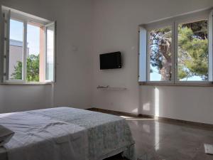 a white bedroom with a bed and two windows at Oasi in Larino