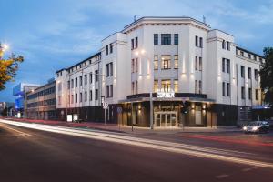 ein großes weißes Gebäude in einer Stadtstraße bei Nacht in der Unterkunft Corner Hotel in Vilnius