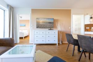 Una sala de estar con una cómoda blanca con un televisor encima. en Quartier 7 App 05, en Ahlbeck