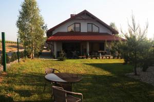 a house with a table and chairs in the yard at Apartamenty Jaśmin i Lilia jez. Sunowo koło Ełku in Chrzanowo