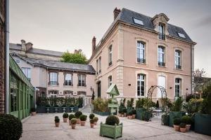 a large building with potted plants in a courtyard at Maleyssie Les Suites in Chartres