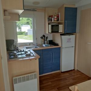 een kleine keuken met blauwe kasten en een witte koelkast bij Smart Home Roma mit Terrasse, Europapark, Rulantica in Boofzheim