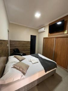 a bedroom with a large bed with a flat screen tv at Casa Lua Flat in Brumadinho