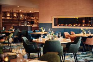 a restaurant with tables and chairs and a fireplace at Hotel van der Valk Wolvega-Heerenveen in Wolvega