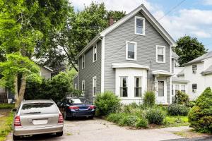 a gray house with a car parked in a driveway at 1 Mi to Needham Center Square: Pet-Friendly Apt! in Needham Heights