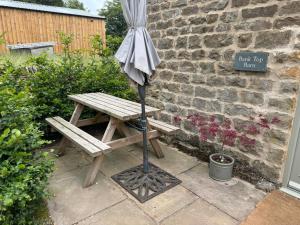 a picnic table with an umbrella next to a brick wall at Bank Top Barn Double Bedroom Self-catering 2 guests in Pickering
