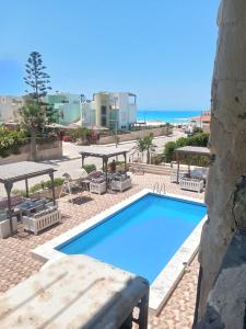 einen blauen Pool mit Blick auf den Strand in der Unterkunft Chalets4A sea and pool view 2Bed rooms without lounge 114 at Green Beach in El-Alamein