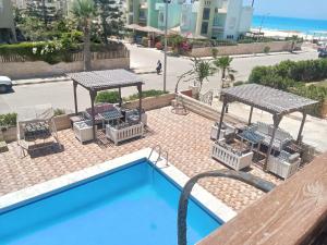 ein Pool mit Tischen und Stühlen neben einem Strand in der Unterkunft Chalets4A sea and pool view 2Bed rooms without lounge 114 at Green Beach in El-Alamein