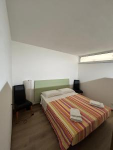 a bedroom with a bed and a chair and a window at Casa Carraia Monolocale in Cembra