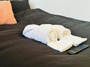 a pile of towels and a remote control on a bed at Smart Artistic studio in shoreditch in Moffat
