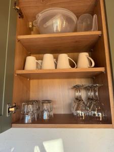 a wooden cabinet with dishes and glasses in it at Apple Blues Farm in Ashford