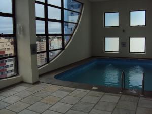 a large swimming pool in a building with windows at Ambassador Residence Apart-hotel in Curitiba