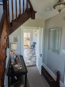 a hallway with a staircase with a table and flowers on it at East Ferry Bed and Breakfast in Brier and Long Islands