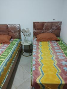 two twin beds in a room with a table at Kelibia ezzahra 2min a pied du plage in Ḩammām al Ghazzāz