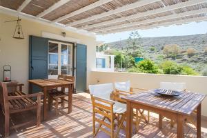 un patio con una mesa y sillas de madera y una mesa y una mesaktopktop en Sunset Retreat Villa Sophia, en Posidhonía