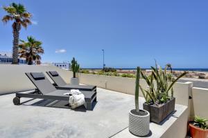 a patio with two chairs and palm trees on a roof at Kokomo beachfront in Cotillo