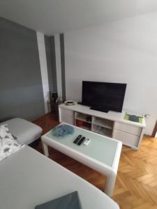a living room with a tv and a white table at Apartmani Lea in Jadranovo