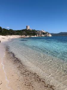 a sandy beach with a lighthouse in the distance at Chez Claudine & Adrien in Figari