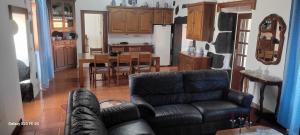 a living room with a leather couch and a kitchen at Cantinho da Vila - AP3 in Santa Cruz da Graciosa