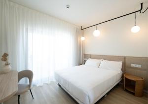 a bedroom with a large white bed and a desk at Hotel RH Arena - Todo Incluido in Gandía