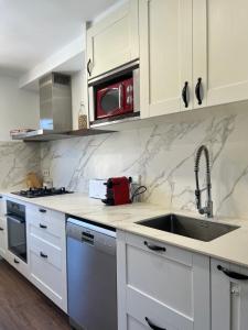 a white kitchen with a sink and a microwave at Maravilloso apartamento en Llívia in Llivia