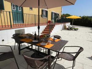 a wooden table with chairs and an umbrella on a patio at Elegant Villa Mello with Beautiful Outdoor Area in Lourinhã