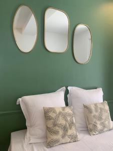 two mirrors on a wall above a bed with pillows at Maison de village - Centre Pérols, terrasse, wifi - Rue calme in Pérols