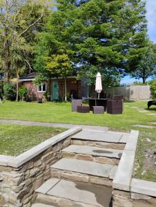 a backyard with a stone retaining wall and a patio at Y Caban-The Cabin-2 Guests-Private Parking-Fast WIFI in Llanelli
