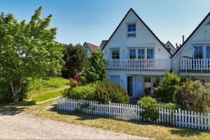 a white house with a white picket fence at Haus Breeghus Ferienwohnung Seekoje in Breege