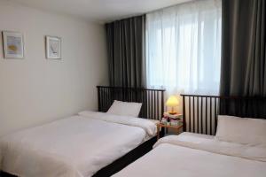 a hotel room with two beds and a window at Stay Hyuga Suwon in Suwon