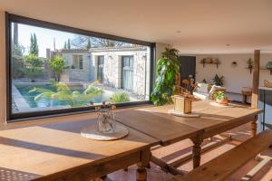 a dining room with a wooden table and a large window at Gîte Lunaben-Maison en pierres avec piscine in Forges