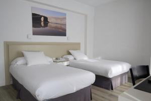 Una habitación de hotel con dos camas y un escritorio. en Hotel Vigo Plaza, en Vigo