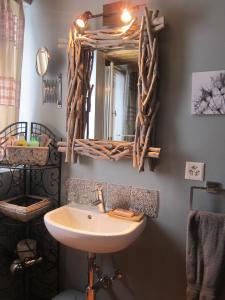 ein Bad mit einem Waschbecken und einem Wandspiegel in der Unterkunft La Demeure des Elfes in Albinen