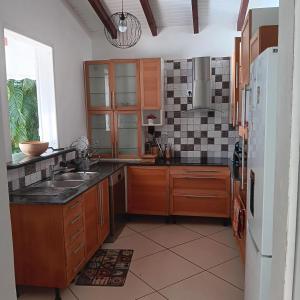 una cocina con fregadero y refrigerador en Villa de la Marina avec vue sur la mer et la montagne, en Gourbeyre