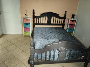 Un dormitorio con una cama de madera en una habitación con tocadores. en Villa de la Marina avec vue sur la mer et la montagne, en Gourbeyre