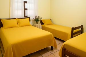2 Betten in einem Zimmer mit gelber Bettwäsche in der Unterkunft Pousada Primavera in Cachoeira Paulista