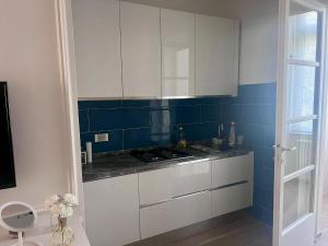 a kitchen with white cabinets and blue tiles at Appartamento Olivia in Viareggio