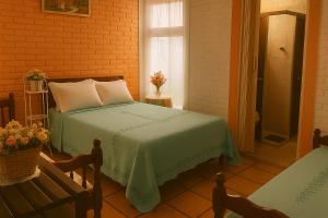 ein Schlafzimmer mit einem Bett mit einer grünen Decke und einem Fenster in der Unterkunft Pousada Primavera in Cachoeira Paulista