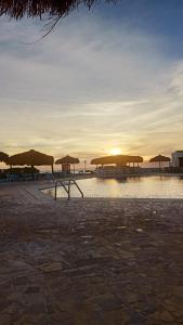 un groupe de parasols sur une plage avec le coucher du soleil dans l'établissement Romantic Chalete قرية الغرندل, à Ras Sudr