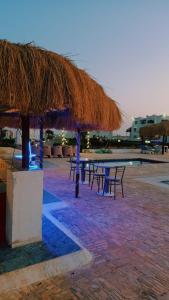 une table de pique-nique avec un parasol en paille sur une plage dans l'établissement Romantic Chalete قرية الغرندل, à Ras Sudr