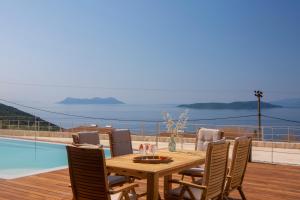 a wooden dining table and chairs with a view of the ocean at 2S Villas Resort - Cave Villas in Sivota