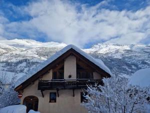 a house with a balcony and snow covered mountains at chaleureux cocon dans les alpes in Le Monêtier-les-Bains