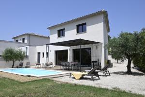 a villa with a swimming pool in front of a house at La Villa Plein Soleil in L'Isle-sur-la-Sorgue